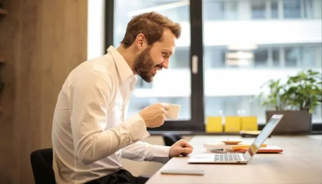 Homem pesquisando "Qual a diferença de Ltda para SLU?" em um notebook.